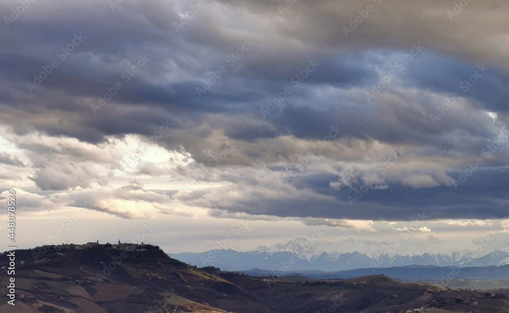 Paese sulle colline grandi nuvole grigie in cielo sopra le valli e le montagne innevate Paese sulle colline grandi nuvole grigie in cielo sopra le valli e le montagne innevate