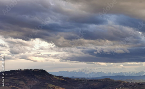 Paese sulle colline grandi nuvole grigie in cielo sopra le valli e le montagne innevate