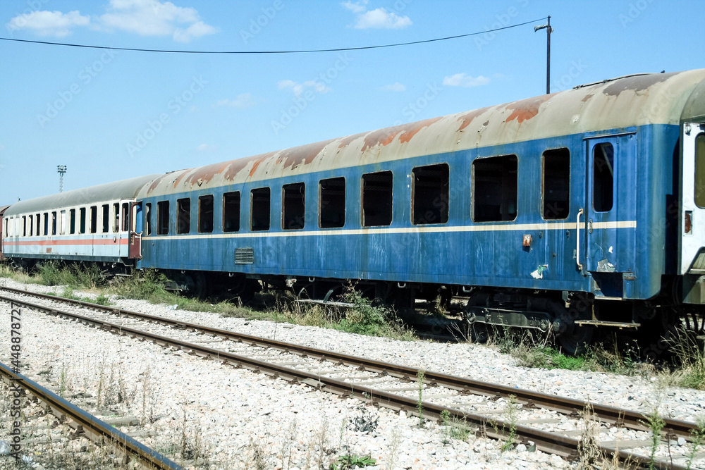 old and rusty abandoned passenger wagons, carriage car, lost and let to rot in a closed train station yard, rusting, after a collapse in traffic and an economic crisis