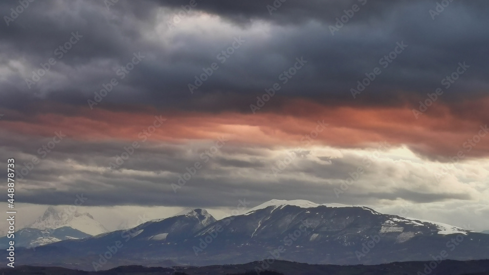 Nuvole rosse sopra le cime innevate dei monti Appennini