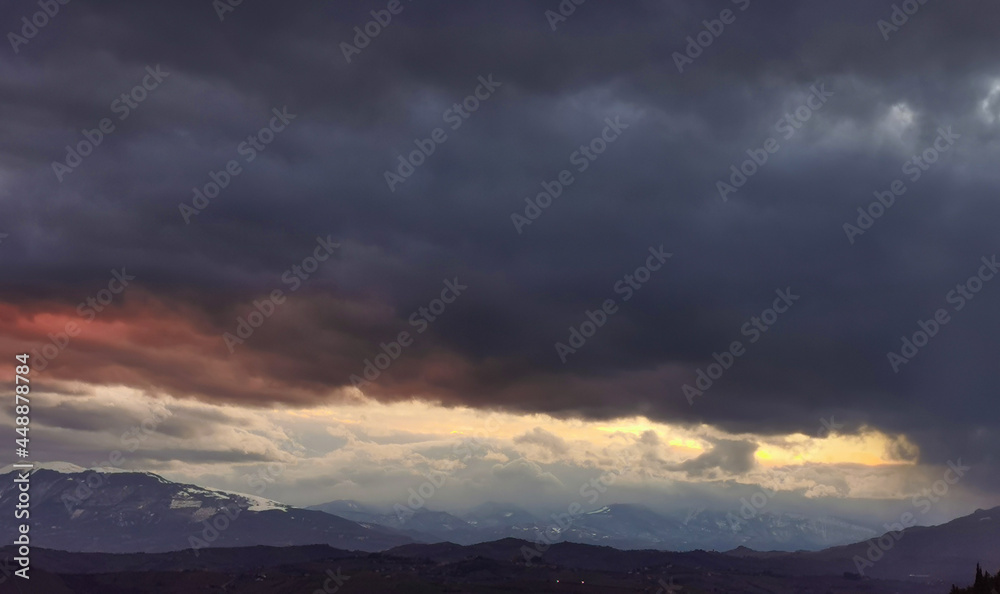 Nuvole rosse sopra le cime innevate dei monti Appennini