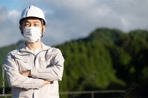 コロナ対応でマスクをする作業着の男性 カメラ目線 コピースペースあり © kapinon