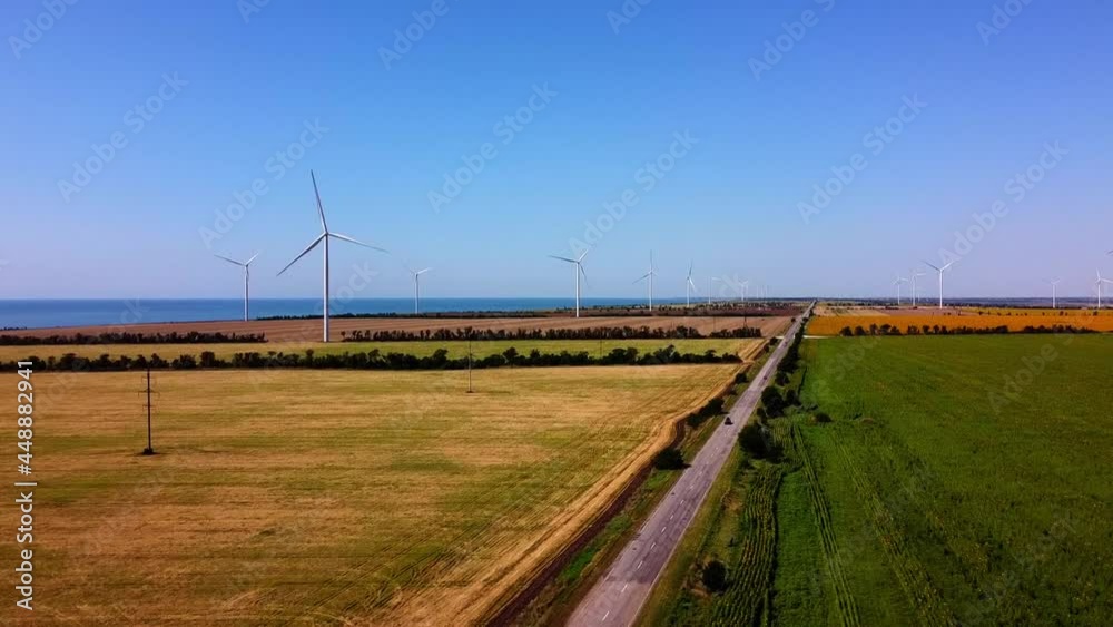 Aerial drone view of a flying over the wind turbine and agricultural fields. Sunflower field. Windmills on the background of the sea. Windmill. Wind farm. Aerial drone view of a flying over the wind turbine and agricultural fields. Sunflower field. Windmills on the background of the sea. Windmill. Wind farm.