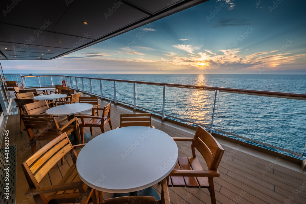 Empty table and chairs by an ocean view at sunset, taken from a cruise ship on vacation