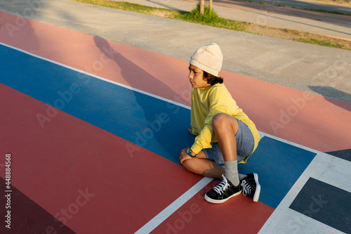 Boy sitting on a basketball court