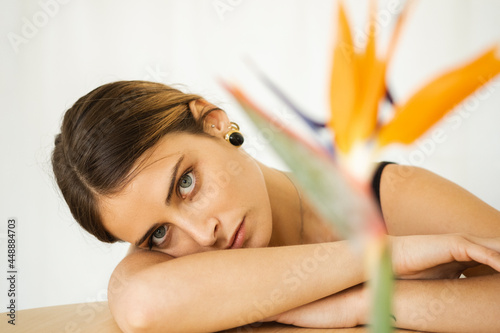 Portrait Of A Young Woman Leaning On A  Behind A Flower photo