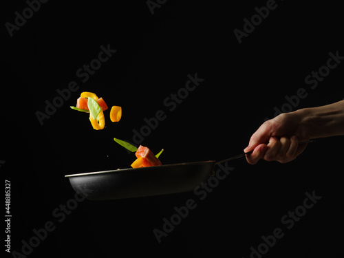 Restaurant dish - red fish with vegetables in a pan. Levitation. Black background. Restaurant and hotel business. Home kitchen. Book of recipes. A beautiful and healthy dish.