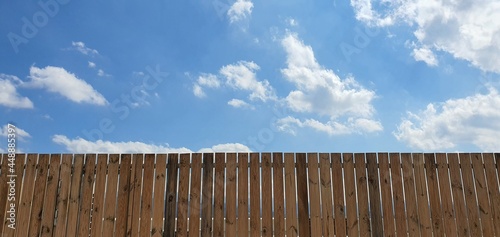 나무 울타리 너머로 보이는 구름이 가득한 파란하늘 A blue sky full of clouds seen through a wooden fence 