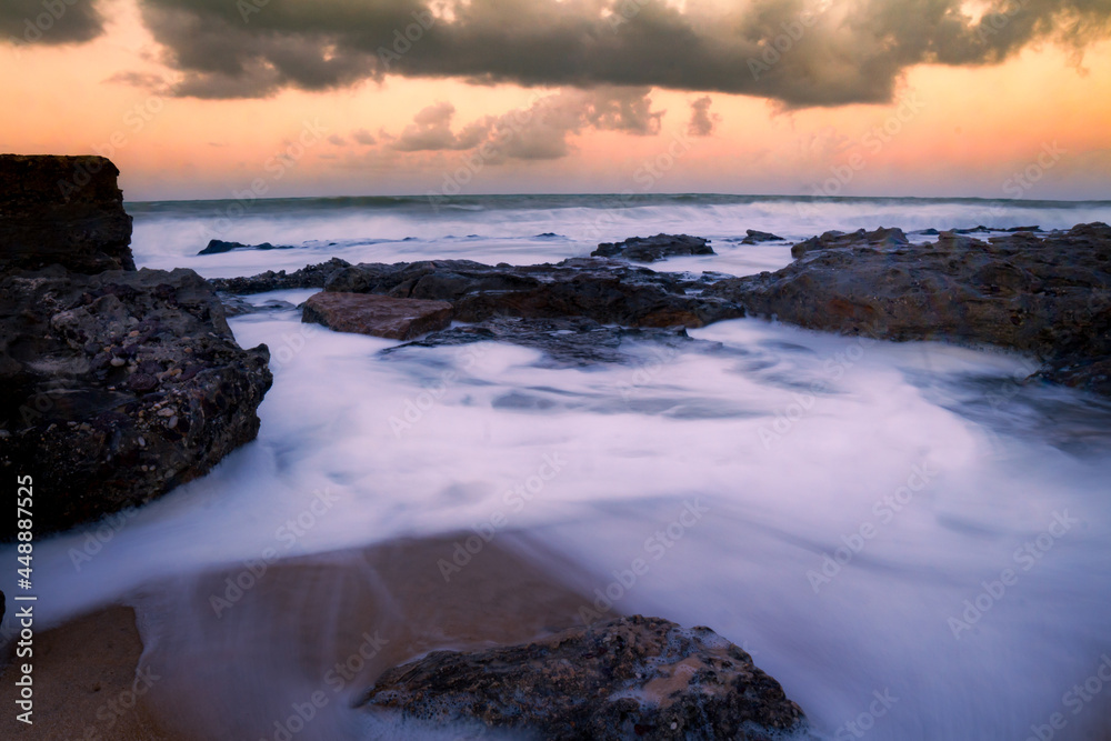 Wake of sea foam left by the waves and the wind. Long exposure seascape during a sunset.