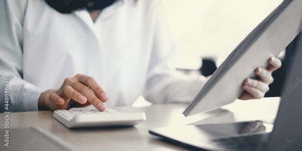 Close-up of a businesswoman using a calculator to audit the company's budget. Tax information is calculated by accountants Close-up of a businesswoman using a calculator to audit the company's budget. Tax information is calculated by accountants