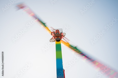 Low angle shot of a colorful spinning attraction on a blue sky background photo