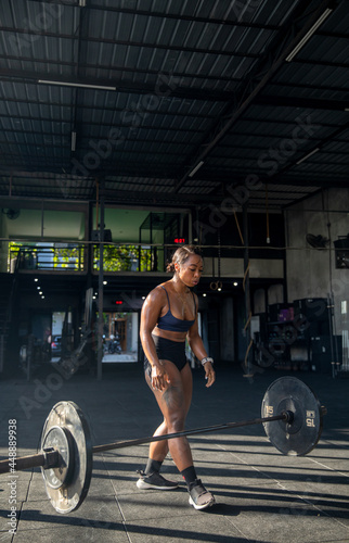 Muscular female athlete lifting heavy weights at gym 