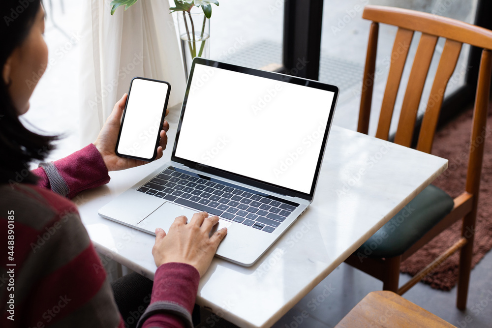 Fototapeta premium computer screen,cell phone blank mockup.hand woman work using laptop texting mobile.with white background for advertising,contact business search information on desk in cafe.marketing,design