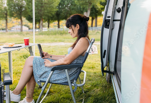 Woman chatting on smartphone in armchair on lawn