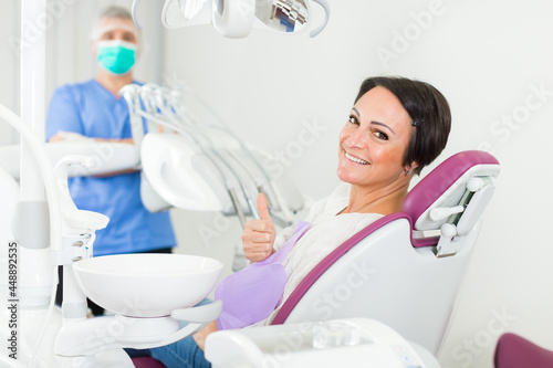 positive patient female thumbs up about work of dantist in medical room photo