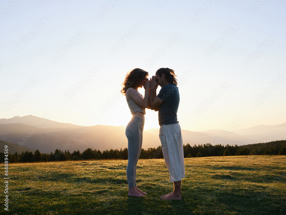 Peaceful couple leaning with foreheads while meditating in mountains Peaceful couple leaning with foreheads while meditating in mountains