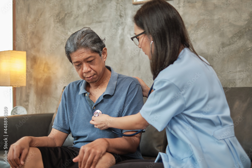 Obraz premium Female doctor checking the health of Asian elderly male patient at home as a medical service for visiting sick older people after retirement, medical support, residential caregiver from professional.