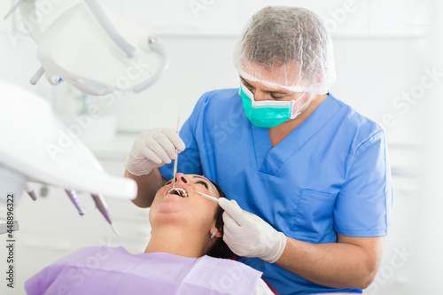 Fototapeta Naklejka Na Ścianę i Meble -  adult dentist checking teeth of patient woman sitting in medical center