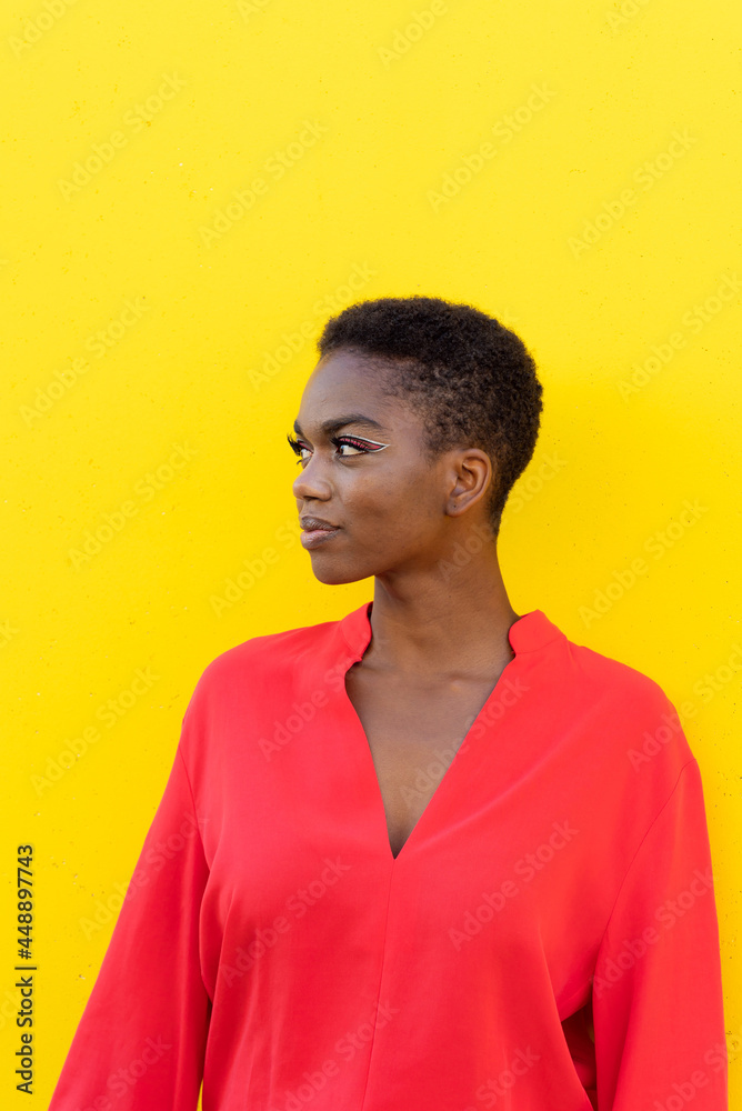 Female with short hair and red suit against yellow wall Female with short hair and red suit against yellow wall