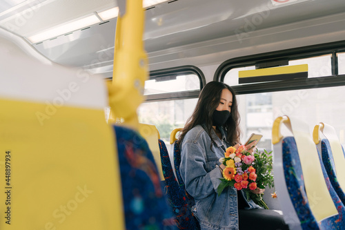 Woman on the Bus with Phone and Flowers photo