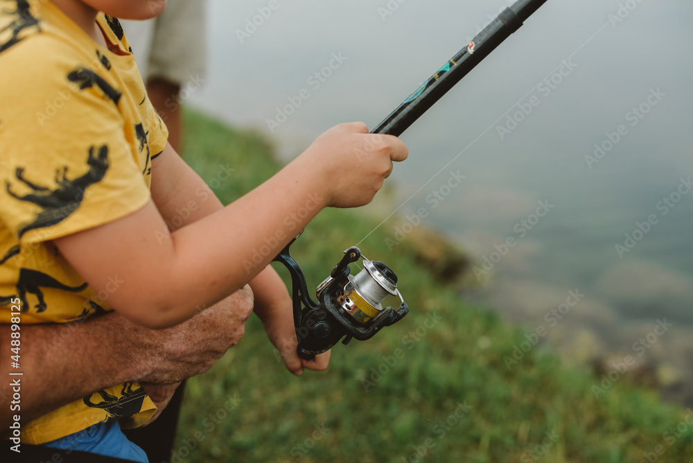 A close-up of hands of father and son holding the rod A close-up of hands of father and son holding the rod