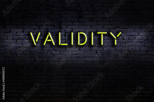 Neon sign. Word validity against brick wall. Night view photo