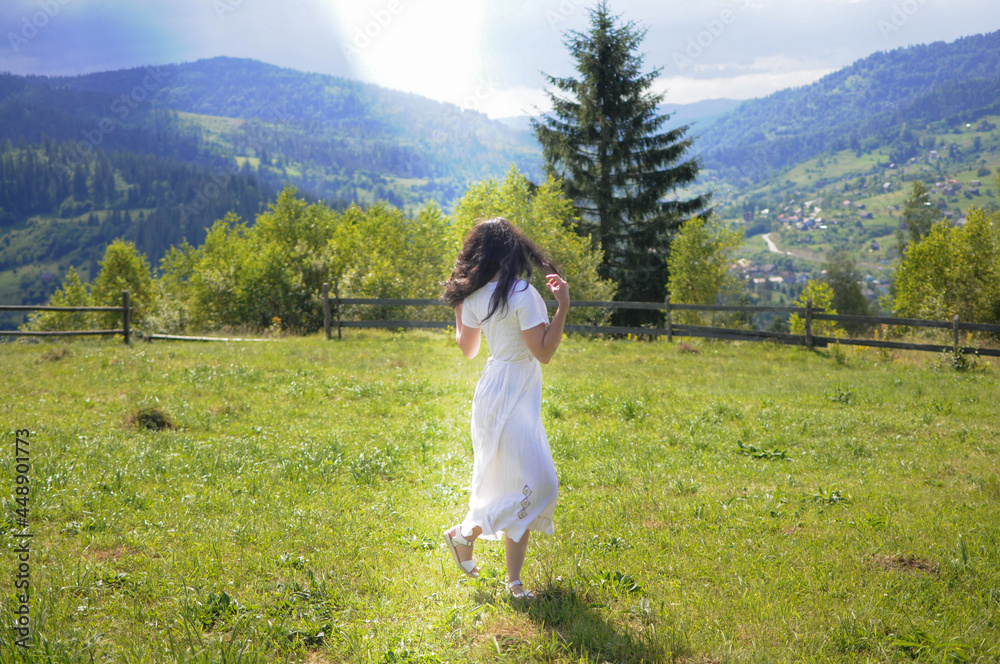 Young woman is walking and jumping on the mountain meadow. Enjoying summertime