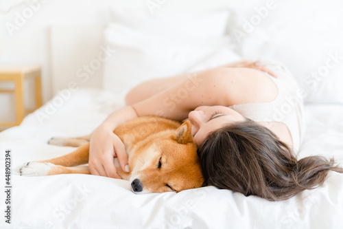Woman cuddle dog in bed