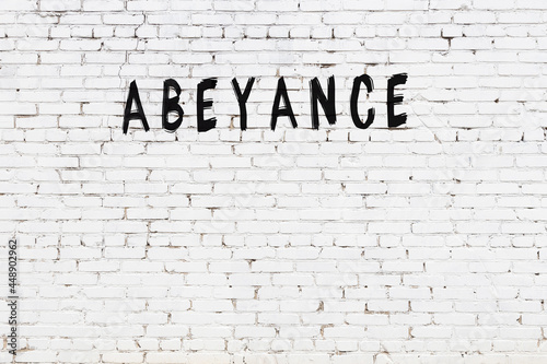 Inscription abeyance painted on white brick wall
