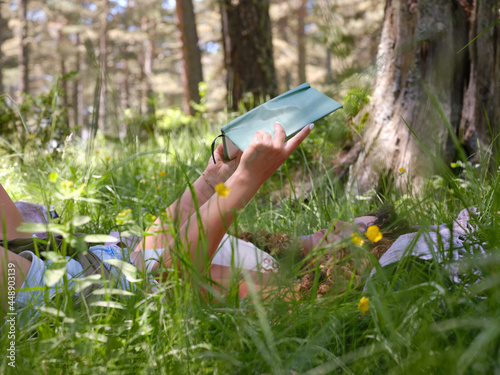 Woman with book in high green grass in woods photo