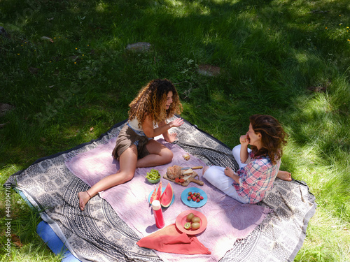 Women enjoying fruit on picnic in summertime photo