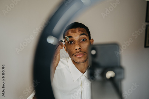 Young man doing beauty routine video tutorial at home photo