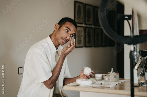 Young man doing beauty routine video tutorial at home