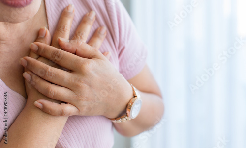 Woman use hand to hole on her chest with pain and suffer face from heart disease. Concept of ST Elevated Myocardial Infarction, with copy space photo