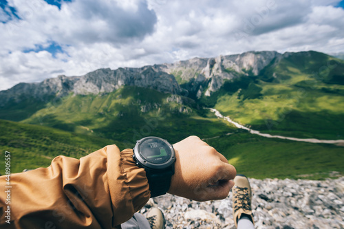 Photos Hiker on high altitude mountain top checking the altimeter on the sports watch
