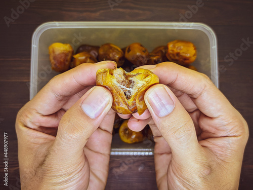 Hand and Fresh brown sukkari dates (kurma sukkari) in plastic box in top view flat lay, studio food photography photo