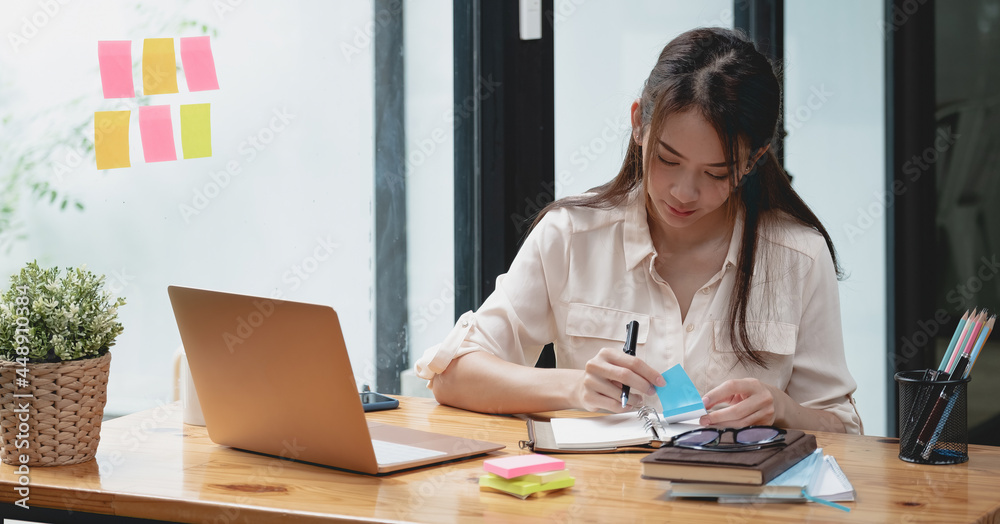 Business asian woman taking note on sticky note, Attractive girl working  with laptop computer Stock-foto | Adobe Stock