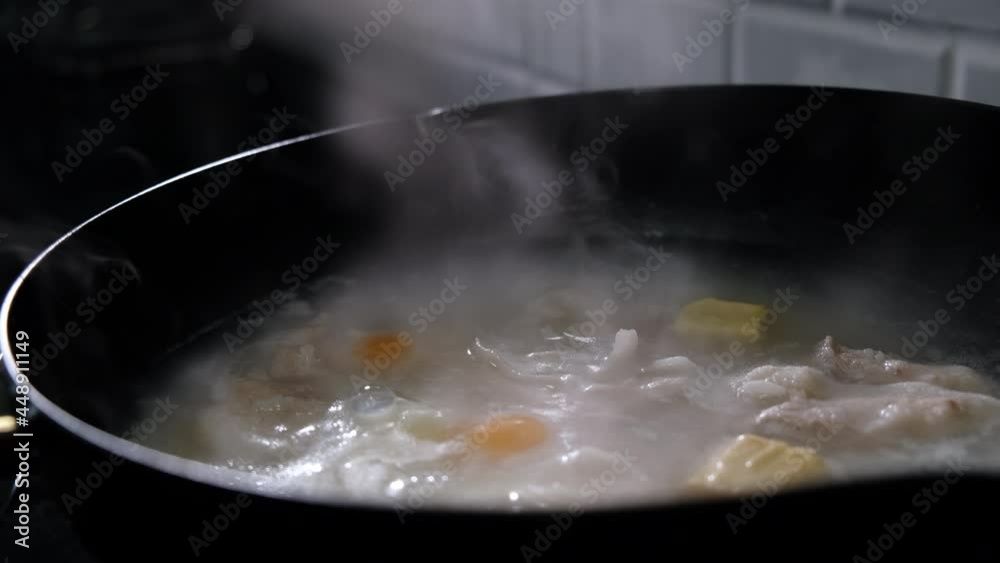 Asian hand close up porridge mush rice with pork in pan on gas stove in the kitchen. Breakfas for family to home Asian hand close up porridge mush rice with pork in pan on gas stove in the kitchen. Breakfas for family to home