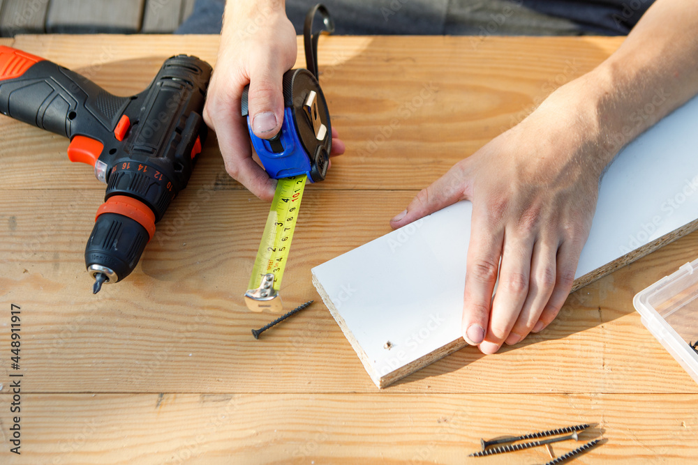 Handyman in blue uniform works with electricity automatic screwdriver. House renovation conception.