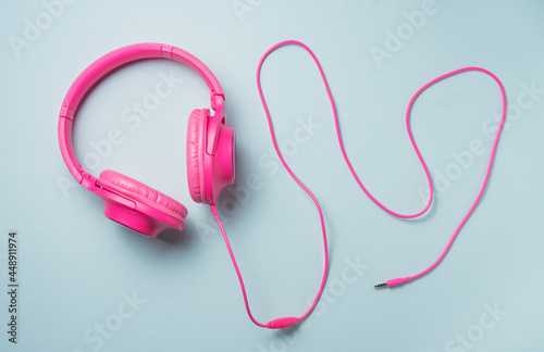 pink large headphones with a wire on a blue background. Top view