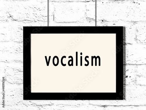 Black frame hanging on white brick wall with inscription vocalism photo