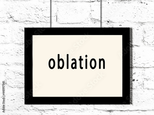 Black frame hanging on white brick wall with inscription oblation