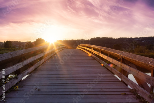 Bridge going over a river in a city park. Dramatic Summer Sunset Sky Art Render. Colony Farm Regional Park, Port Coquitlam, Vancouver, British Columbia, Canada.