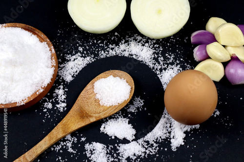 Flat lay vintage wooden spoon and has salt onions egg on it in black background