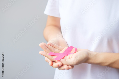 October Breast Cancer Awareness month, elderly Woman in white T- shirt with hand holding Pink Ribbon for supporting people living and illness. International Women, Mother and World cancer day concept