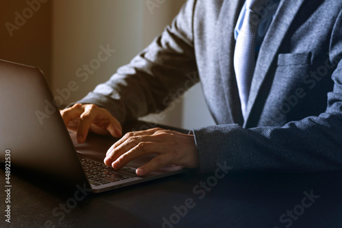 Close up of young businessman working on a laptop on dark background