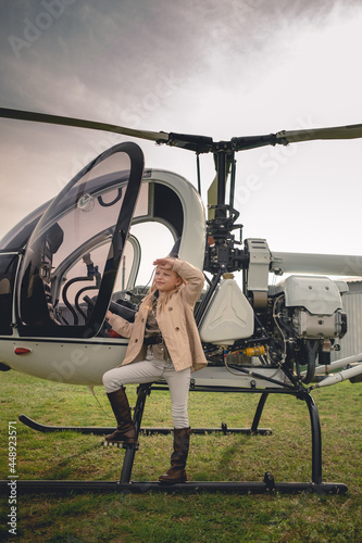 Blonde tween girl near helicopter looking into distance photo