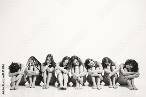 Girls with different types in one photo. The girls sit on the floor and hug themselves by the legs. A place for a text on female psychology. Understanding Female Psychology