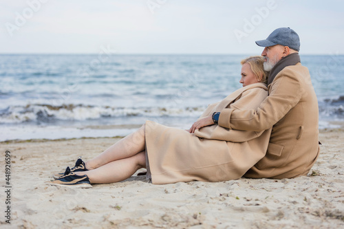 aged couple sitting on the beach near the sea