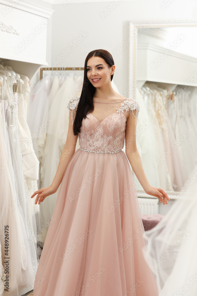 Woman trying on beautiful wedding dress in boutique Woman trying on beautiful wedding dress in boutique